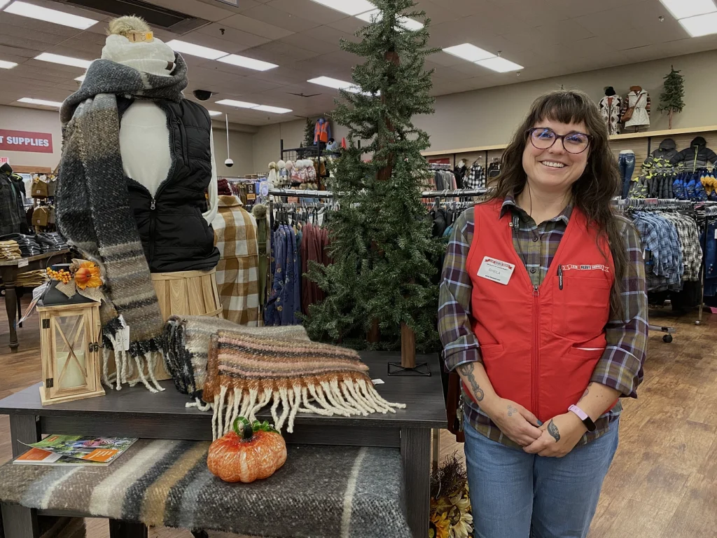 Female L&M employee smiling next to merchandise.